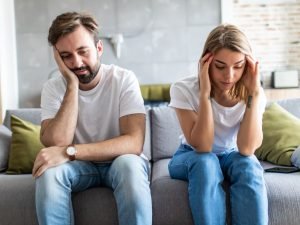 Portrait of couple are sitting on couch and are quarreling with each other.